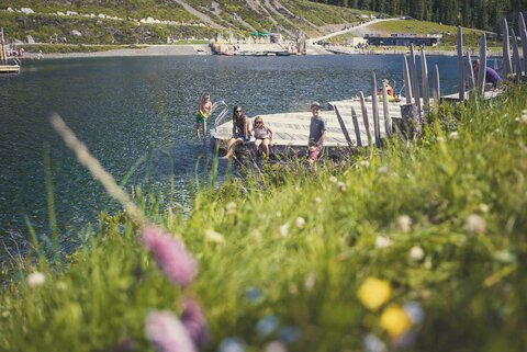 Eine Familie sitzt auf dem Steg am Fichtensee. 