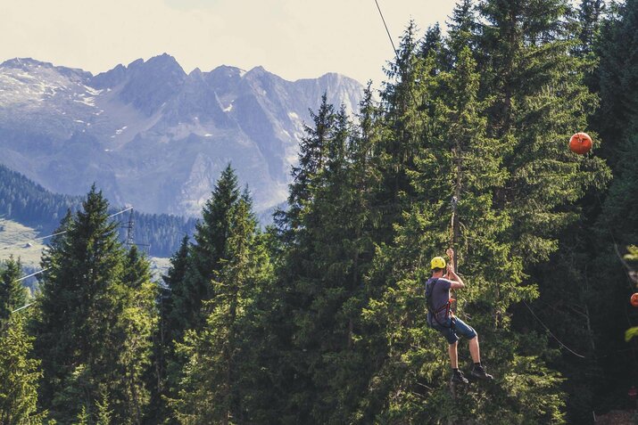 Eine Mann fährt mit einer Seilrutsche durch den Wald