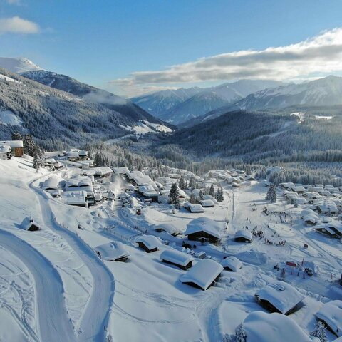 Lage & Anreise Blick auf ein schneebedecktes Dorf mit verschneiten Häusern und winterlichen Landschaften