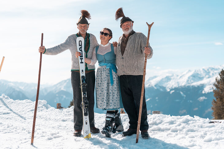 Zwei Männer und eine Frau in Trachtenkleidung im Schnee