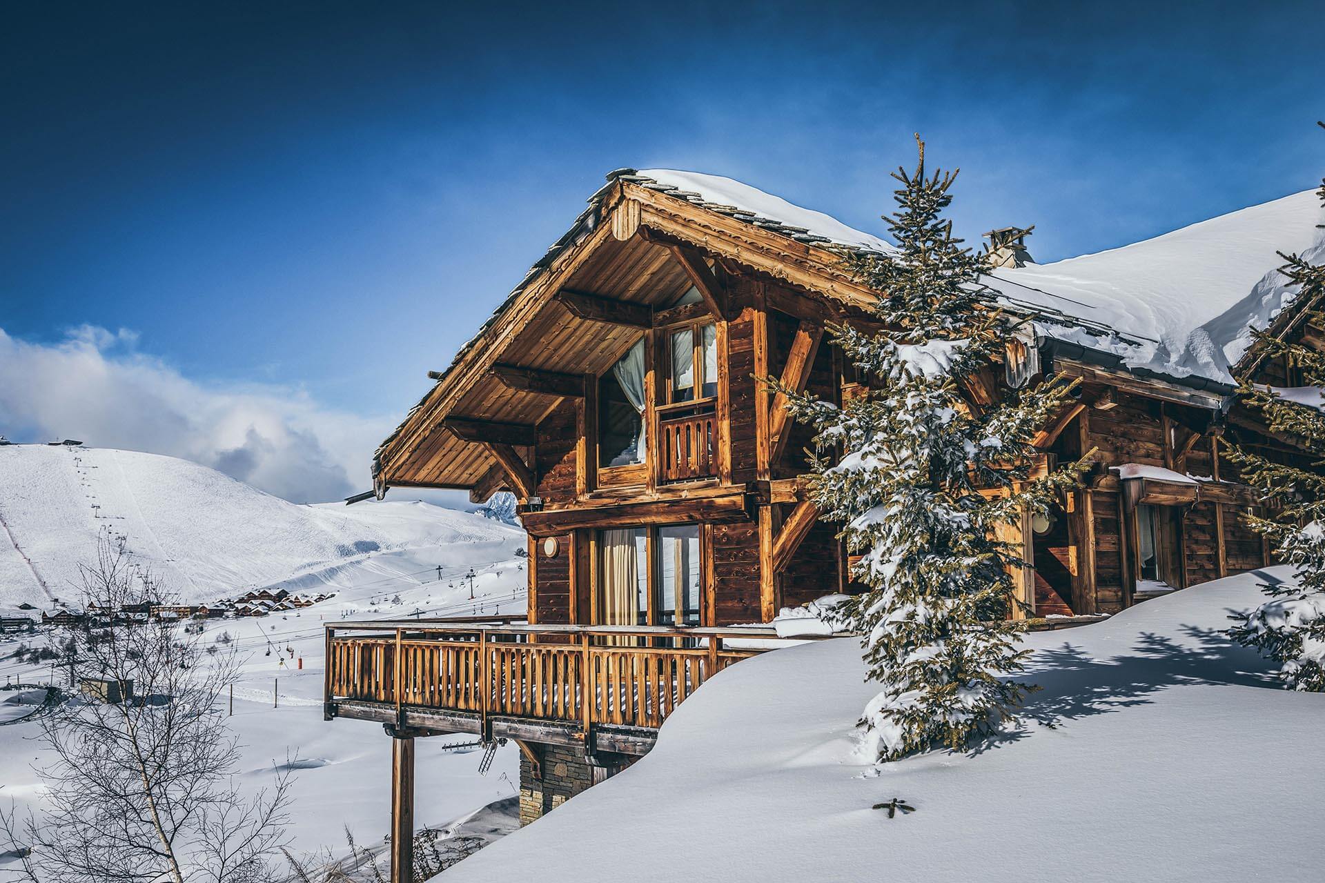 Holzhaus, das von Schnee bedeckt ist, mit winterlicher Atmosphäre und verschneiten Bäumen rundherum